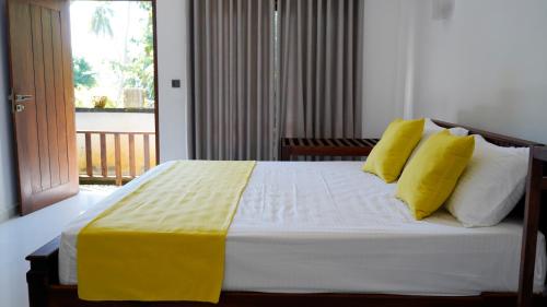 a bedroom with a bed with yellow and white pillows at Sea Bay Inn Tangalle in Tangalle