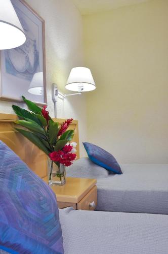 a bedroom with two beds and a vase with red flowers at Plum Tree Club in Bridgetown