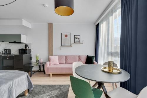 a living room with a pink couch and a table at RentPlanet - Apartamenty Chlebova in Gdańsk