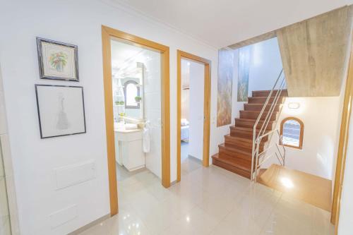 a white bathroom with a staircase and a sink at Can Quart in Alcudia