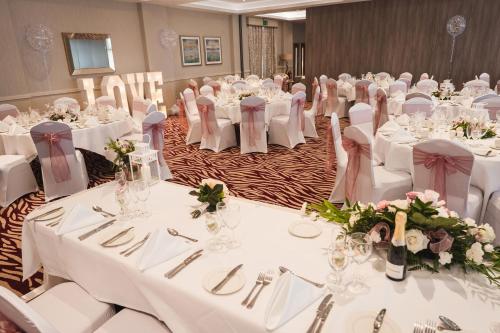 a banquet hall with white tables and white chairs at Ramsey Park Hotel in Ramsey
