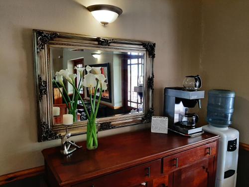 a mirror on a wooden dresser with flowers in a vase at Karoo Life B&B in Calitzdorp