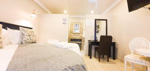a bedroom with a bed and a desk and a sink at Le Grant Guesthhouse in Kroonstad