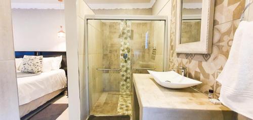 a bathroom with a shower and a sink and a bed at Le Grant Guesthhouse in Kroonstad