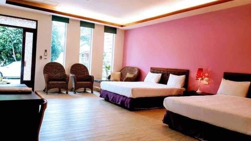 a bedroom with two beds and a pink wall at 獨棟山水心旅棧 in Kenting