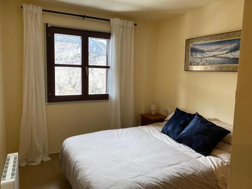 a bedroom with a bed with blue pillows and a window at Roxy House - Apartamento a pie de pistas de Espot in Espot