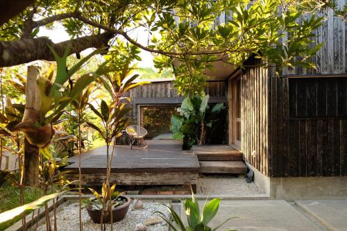 a house with a garden with trees and a porch at 姉と弟の家 in Nanjo