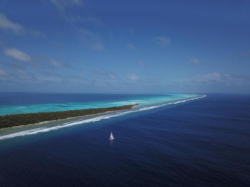 an island with a sailboat in the middle of the ocean at Island Luxury Boutique Hotel - Fulhadhoo in Fulhadhoo