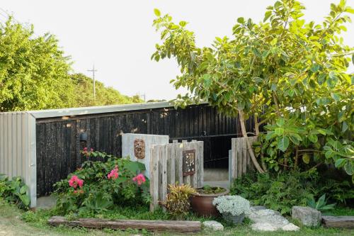 a garden with a fence and a tree and flowers at 姉と弟の家 in Nanjo