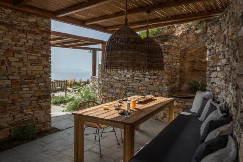 a wooden table in a patio with a stone wall at Verina Astra in Artemonas