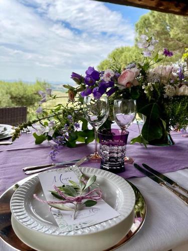 a table with a plate and wine glasses and flowers at Agriturismo Sole in Trequanda