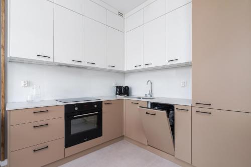 una cocina con armarios blancos y un aparato negro en Lotniczówka Apartments by Renters Prestige, en Cracovia