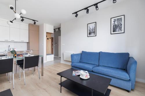 a living room with a blue couch and a table at Lotniczówka Apartments by Renters Prestige in Krakow
