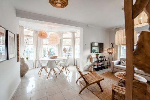 a white living room with a table and chairs at South Beach House in Zandvoort