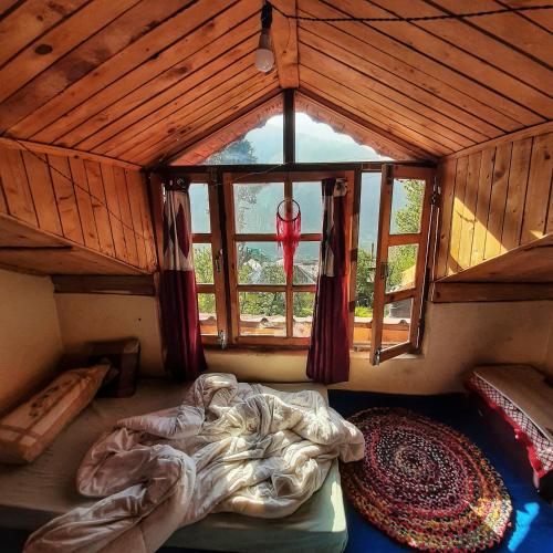 an attic room with a bed and a window at The cottage and cheese in Manāli
