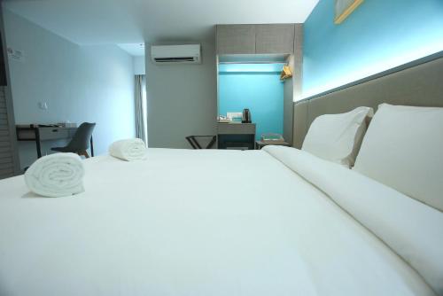 a bedroom with a large white bed and a desk at Stanton City Hotel in Kota Kinabalu