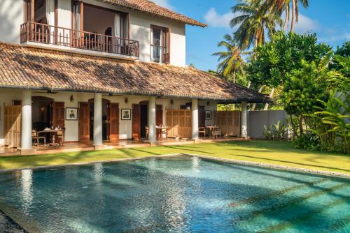 a villa with a swimming pool in front of a house at Sundara by Mosvold in Balapitiya