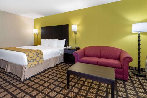 a hotel room with a bed and a chair at Baymont by Wyndham Queensbury/Lake George in Queensbury