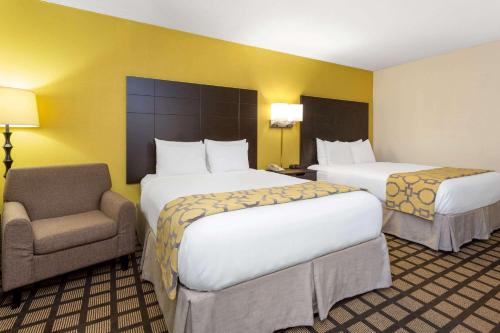 a hotel room with two beds and a chair at Baymont by Wyndham Queensbury/Lake George in Queensbury
