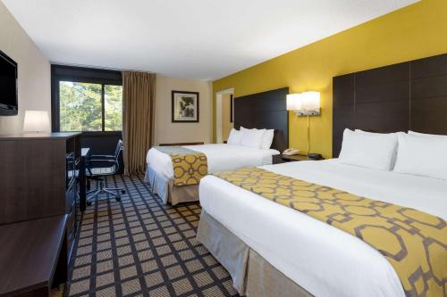 a hotel room with two beds and a desk at Baymont by Wyndham Queensbury/Lake George in Queensbury