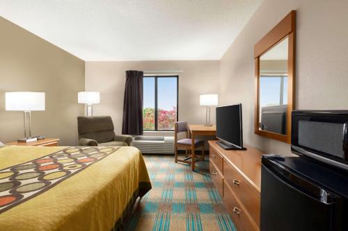 a hotel room with a bed and a flat screen tv at Super 8 by Wyndham Hannibal in Hannibal