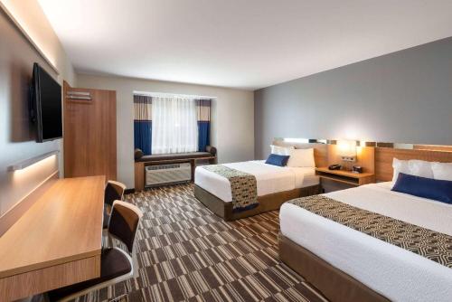 a hotel room with two beds and a flat screen tv at Microtel Inn & Suites by Wyndham Warsaw in Warsaw
