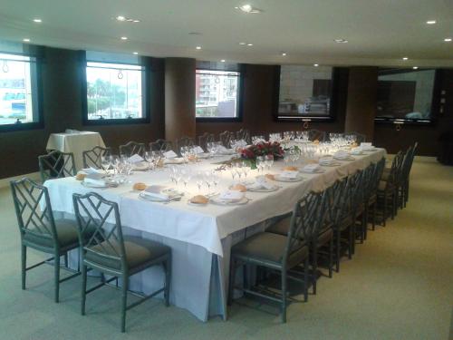 a long table with chairs and plates and wine glasses at Hotel Bahía in Santander
