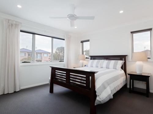 a white bedroom with a large bed and windows at Birubi Breezes 2 Large Duplex with Air Conditioning WI FI and only 5 minute walk to the beach in Anna Bay