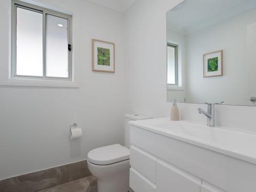 a white bathroom with a toilet and a sink at Birubi Breezes 2 Large Duplex with Air Conditioning WI FI and only 5 minute walk to the beach in Anna Bay