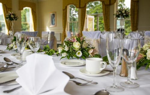 a table with white table cloths and glasses on it at Grinkle Park Hotel in Loftus