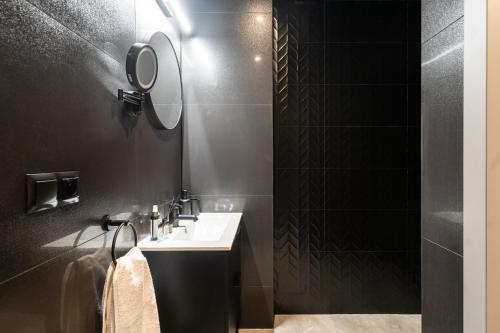 a black bathroom with a sink and a mirror at Apartament Królowa Luiza in Zabrze