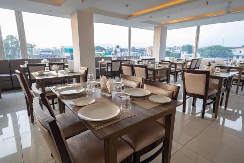 a dining room with tables and chairs and windows at Hotel Alaya in Dehradun