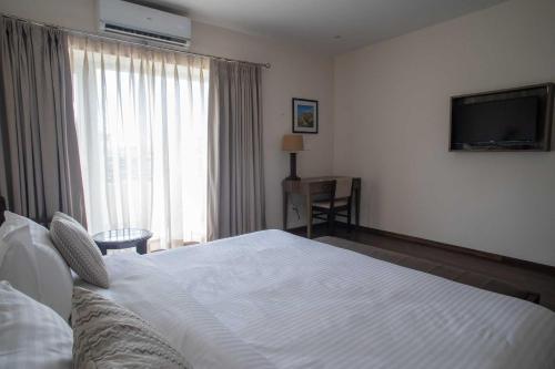 a bedroom with a white bed and a television at Hotel Alaya in Dehradun
