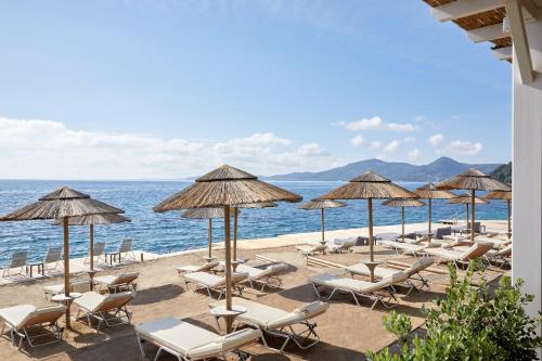 a bunch of chairs and umbrellas on a beach at MarBella, Mar-Bella Collection in Agios Ioannis Peristeron