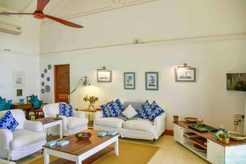 a living room with white furniture and a ceiling fan at Tamarind Tree Zanzibar in Mazizini