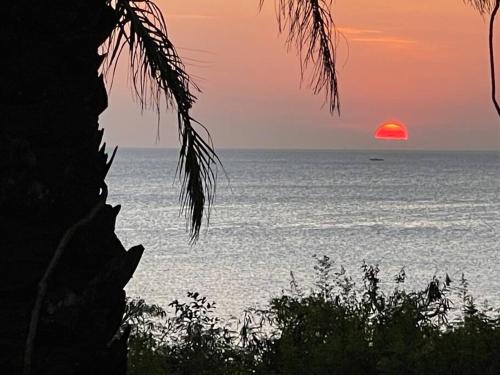 a sunset over the ocean with a boat in the water at Tamarind Tree Zanzibar in Mazizini