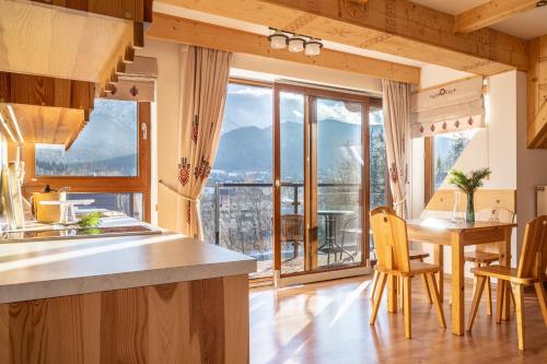 a kitchen with a table and chairs and a large window at Apartament Szymoszkowa in Zakopane
