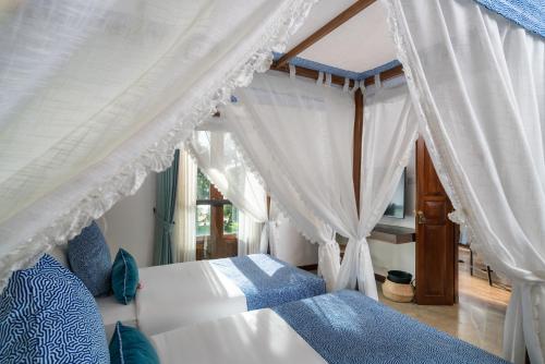 a bedroom with a canopy bed with white curtains at Sundara by Mosvold in Balapitiya