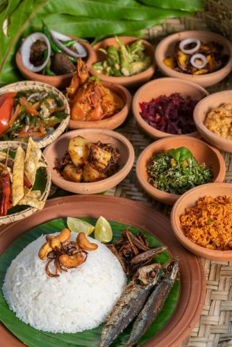 a table topped with plates of food with rice and vegetables at Sundara by Mosvold in Balapitiya