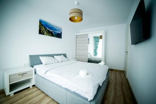 - une chambre avec un lit blanc et une télévision dans l'établissement Kasper Escape, à Braşov