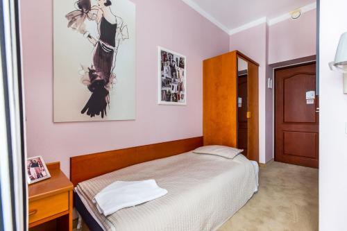a small bedroom with a bed and a wooden cabinet at Willa Excelsior in Zakopane