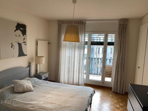 a bedroom with a bed and a sliding glass door at Genève, plein centre,belle vue Lac, splendide et grand appartement in Geneva
