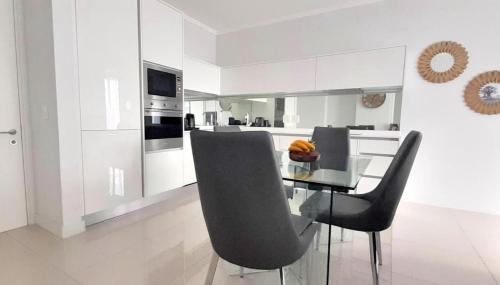 een keuken met een glazen tafel en zwarte stoelen bij Waterfall Luxury Apartment in Midrand