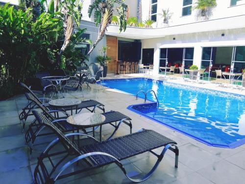 a swimming pool with tables and chairs next to a building at Hotel Serra de Jundiaí in Jundiaí