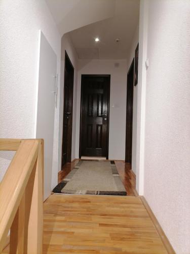 a hallway with white walls and wooden floors and a door at Zeleni svet 2 in Crni Vrh