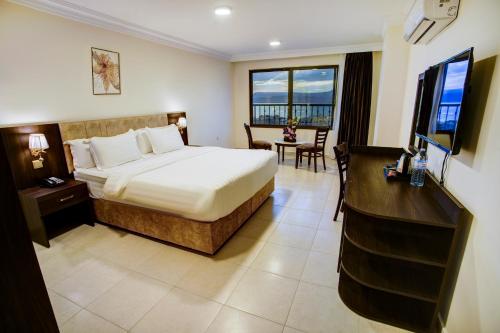 a hotel room with a bed and a desk and window at AQABA COAST HOTEL in Aqaba