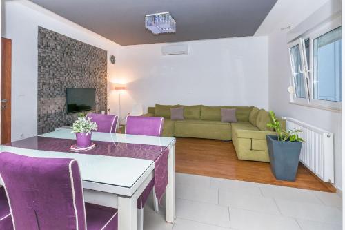 a living room with a couch and a table and purple chairs at Apartment Mario in Strožanac