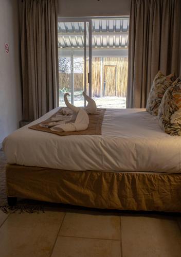 a bed with two towels on it with a window at Tshikwalo Game Lodge in Klipdrift
