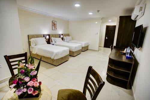 a hotel room with two beds and a table with flowers at AQABA COAST HOTEL in Aqaba