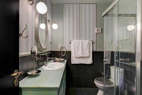 a bathroom with a sink and a toilet and a mirror at Volhon Mansions of Parnassos in Eptalofos